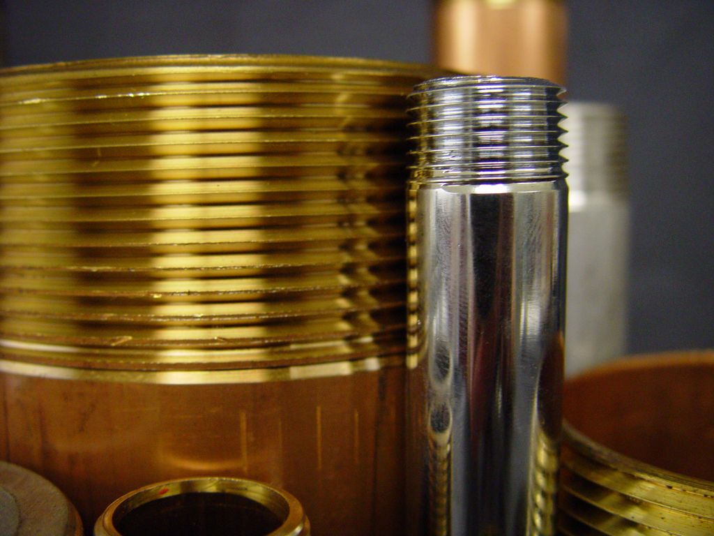 Brass and chrome pipe nipples with threaded ends — close-up detail